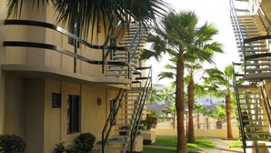 A building with a central courtyard, palm trees, and a staircase leading to an upper level.