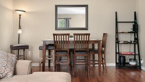 Un comedor con una mesa y sillas, una lámpara, una estanter ía y un sofá.