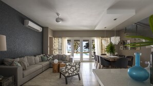 Una sala de estar moderna con un sofá, un sillón estampado, una mesa de centro y un comedor con una mesa y sillas.