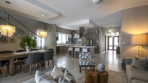 Una sala de estar moderna con comedor, cocina y escalera.