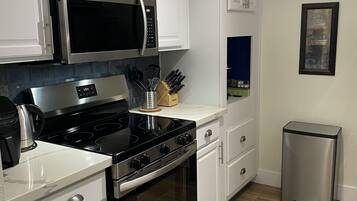 A modern kitchen with white cabinetry, stainless steel appliances, and a herringbone wood floor.