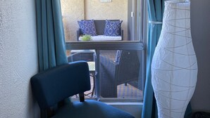 Een kamer met uitzicht op een terras, een stoel, een lamp en een bord aan de muur.