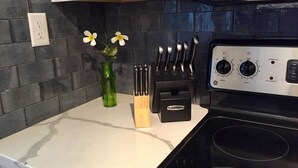 Een keuken met een zwarte kookplaat, een messenblok en een vaas met bloemen op het aanrecht.