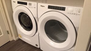 Two white Whirlpool front-loading washing machines in a laundry room with wooden flooring. - Ski In/out For Both Downhill And Cross-country (Vernon)