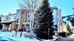 Un edificio de varios pisos con un estilo arquitectónico moderno, que presenta una combinación de fachadas de vidrio y metal.