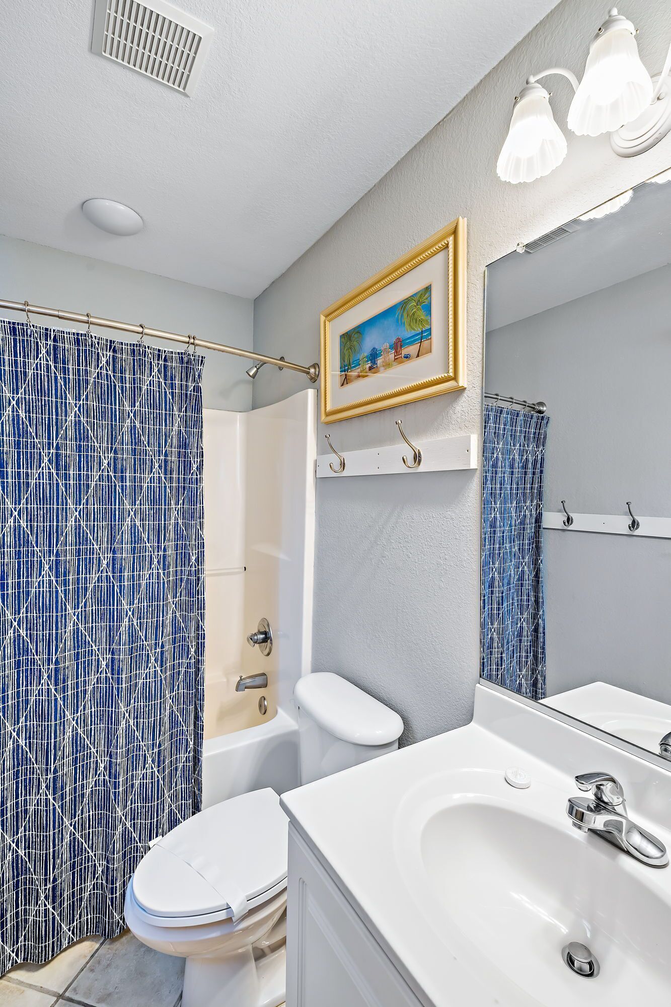 A bathroom with a shower, toilet, sink, and a mirror.