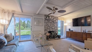 A living room with a stone fireplace, a glass coffee table, a sofa, a television, and a ceiling fan. - Townhouse near GTNP and Yellowstone -Spectacular Views - 2-3 bed-2 bath (Jackson)