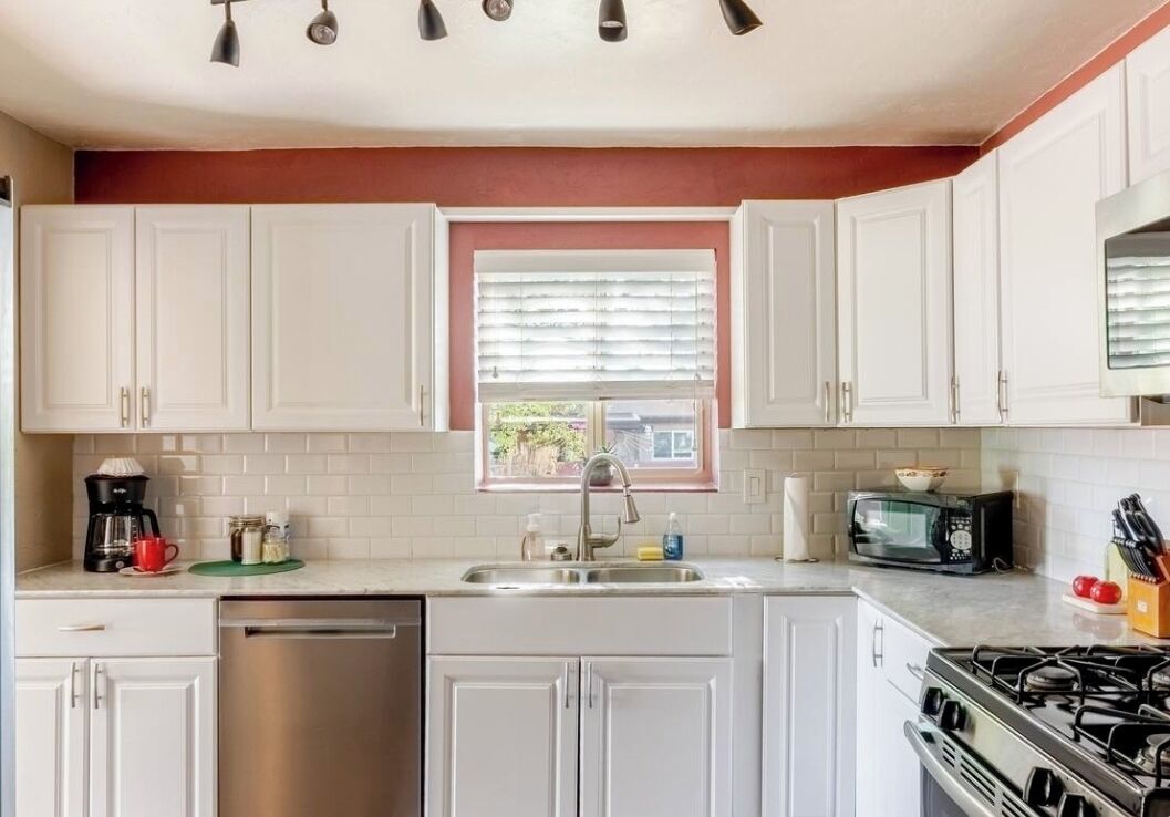 A kitchen with white cabinets, a stainless steel dishwasher, a microwave, and a gas stove.