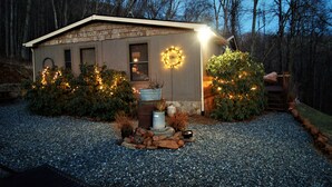 A small house with a gravel driveway, surrounded by greenery and a wreath on the door.