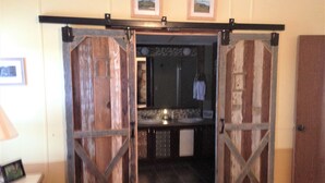 A rustic bathroom with wooden doors, a sink, and a mirror.