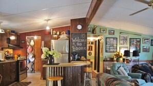 A kitchen with a refrigerator, a bar area, and a dining area with chairs and a table.