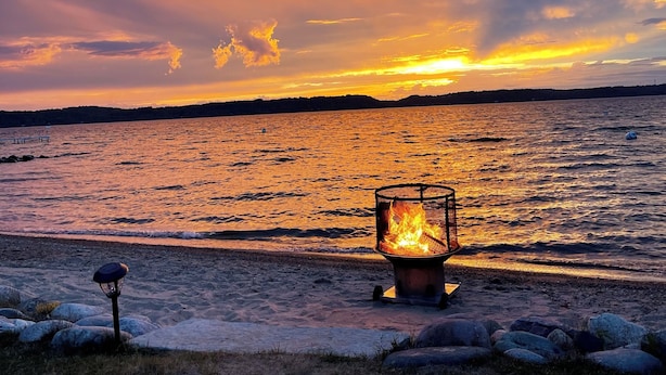A beach scene with a fire pit and a lamp post.
