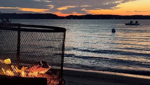 A fire pit by a lakeside at sunset.