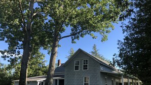 A two-story house with a stone facade, a chimney, and a porch with white columns.
