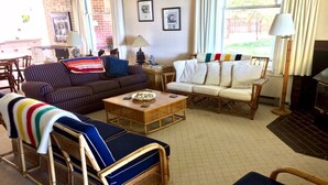 A cozy living room with a sofa, armchairs, a coffee table, and a fireplace.