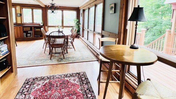 Une pièce spacieuse comprenant une grande table à manger en bois, une table ronde avec des chaises et un tapis à motifs.