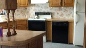 A compact kitchen with wooden cabinets, a refrigerator, a stove, and a dishwasher. - Beautiful Sunsets, Trails, Wildlife and All Out of Doors to enjoy (Atlanta)