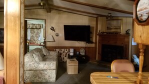 A living room with a sofa, a television, a fireplace, and a table with a pen. - Beautiful Sunsets, Trails, Wildlife and All Out of Doors to enjoy (Atlanta)