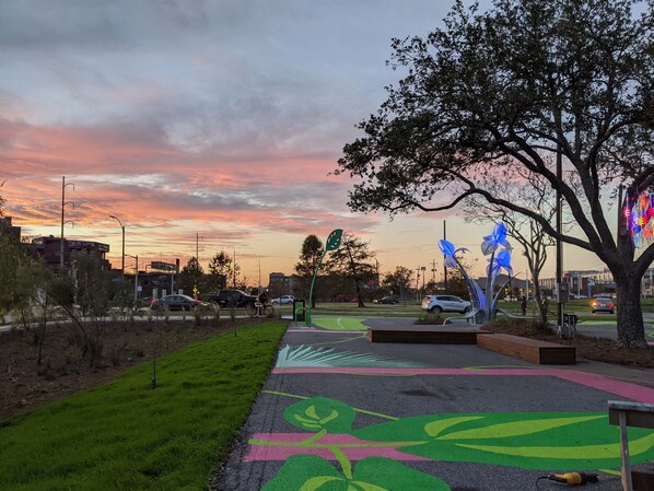 Un parque con senderos verdes, árboles y un cielo al atardecer.