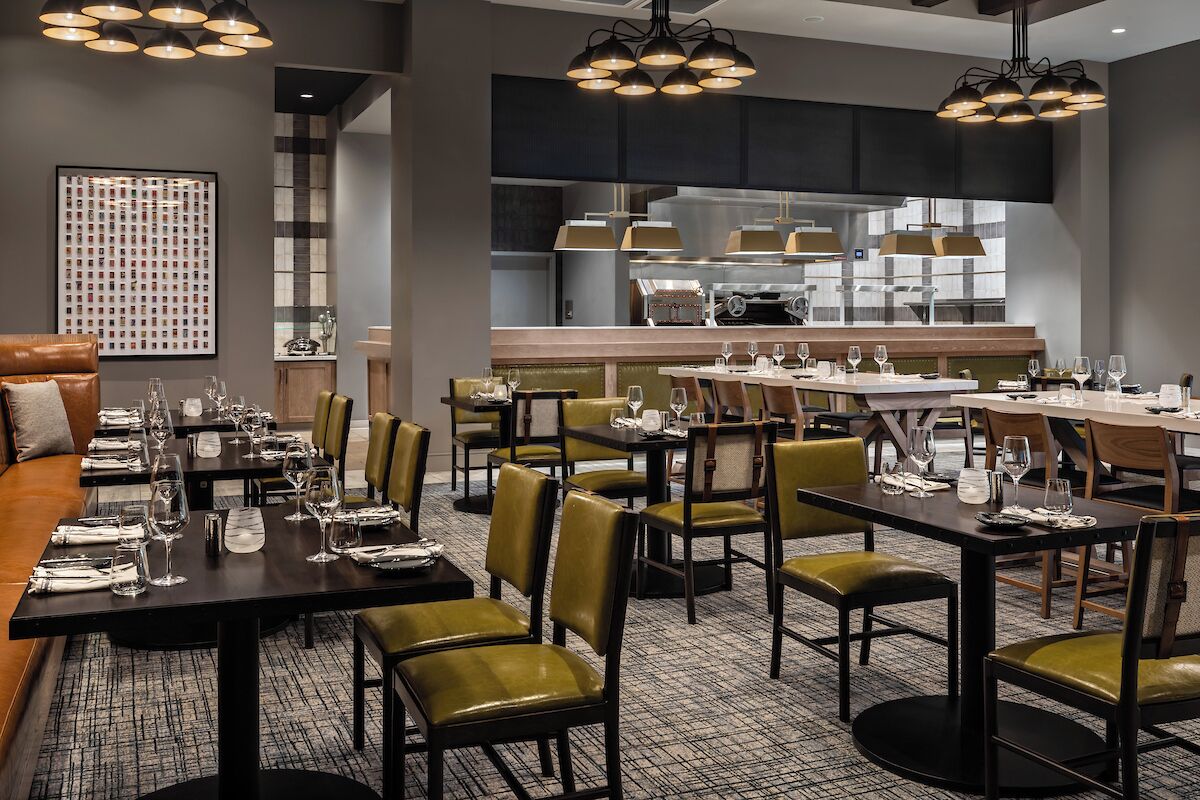 A restaurant with multiple dining tables, chairs, and a bar area.