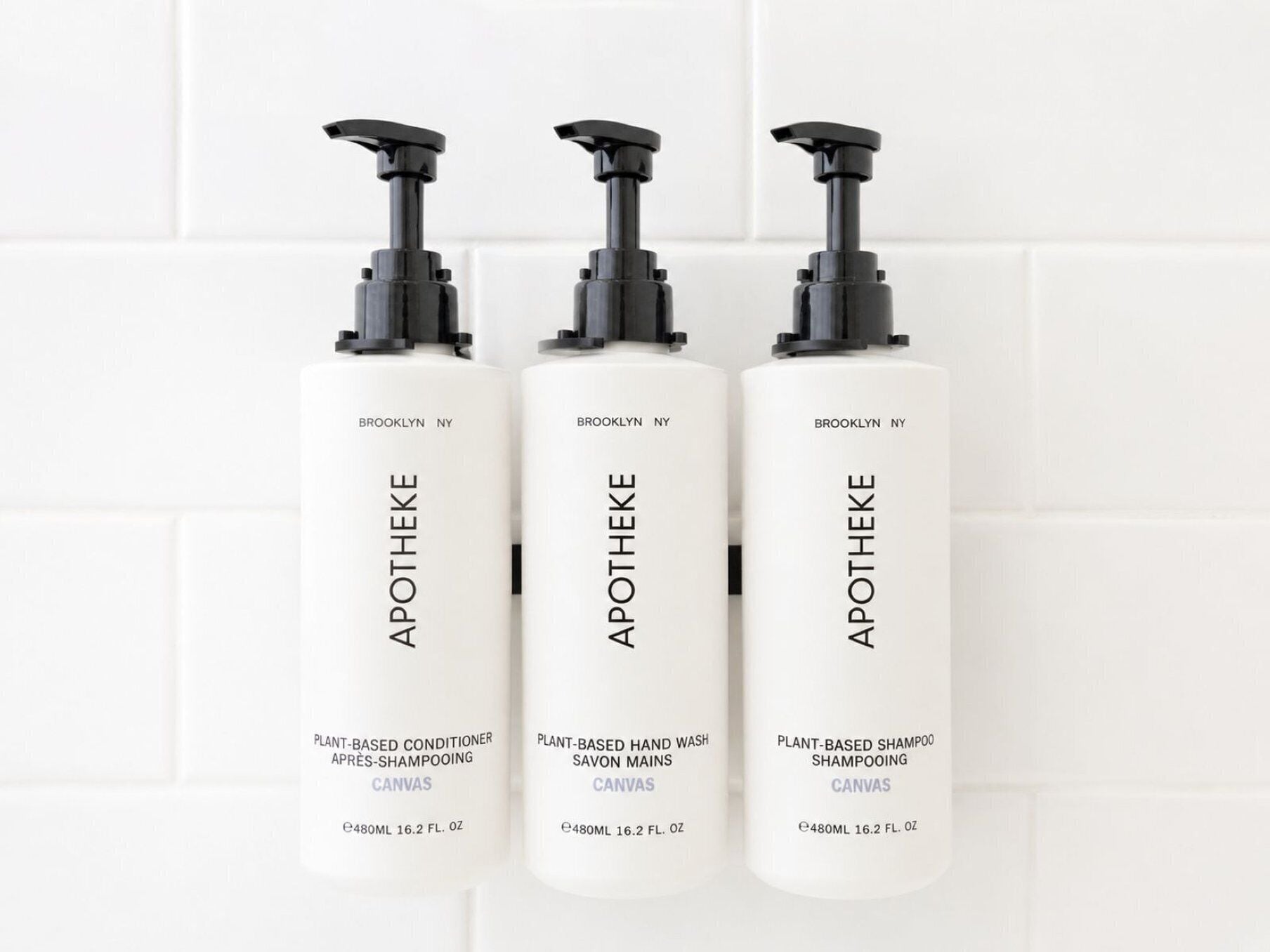 Three bottles of Apotheke plant-based products against a white tiled wall.