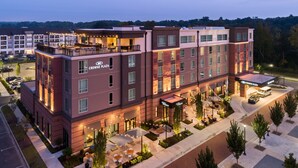 A hotel with a modern design, featuring a rooftop bar and outdoor seating area.