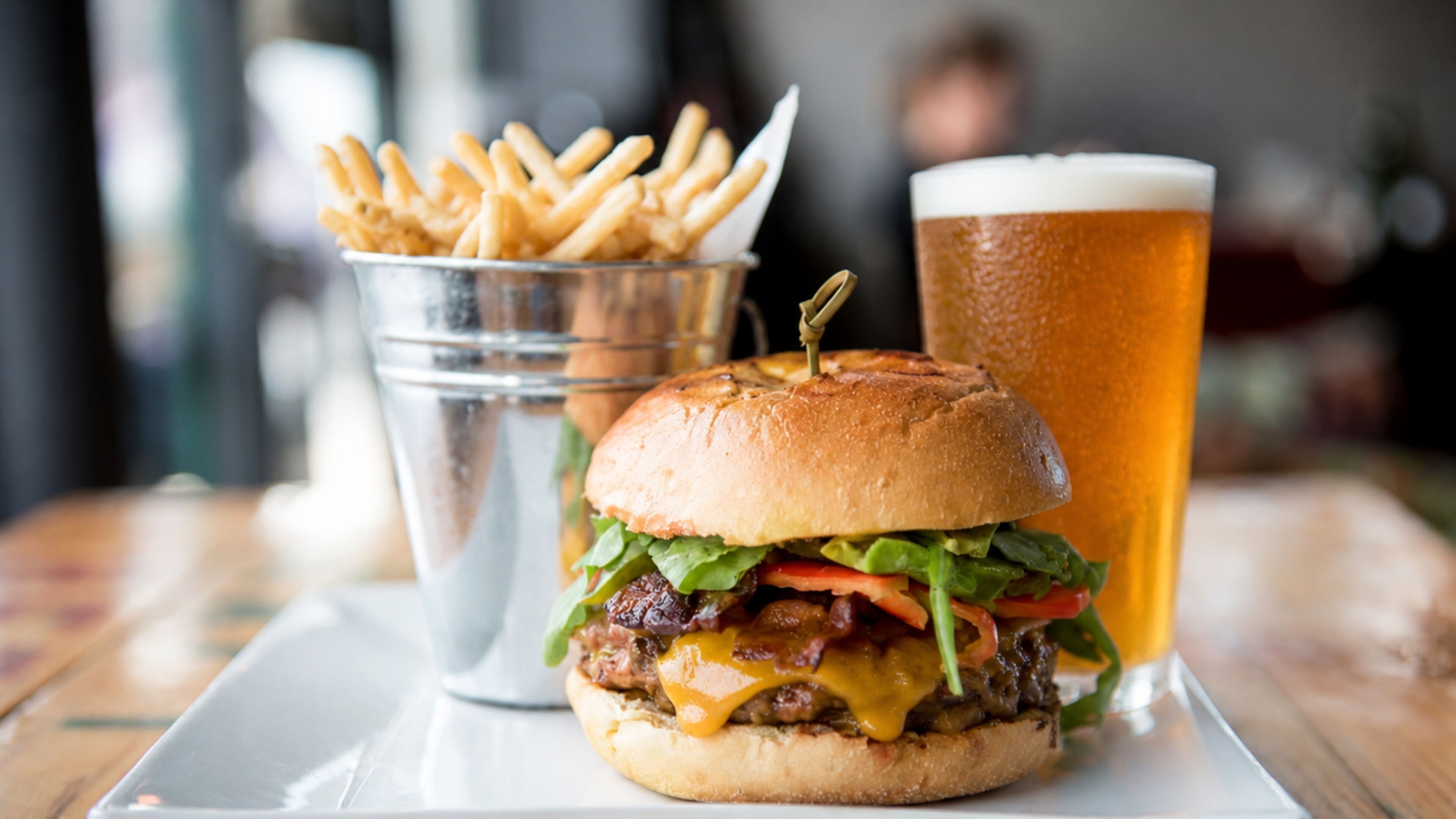 A burger with fries and a glass of beer on a table.