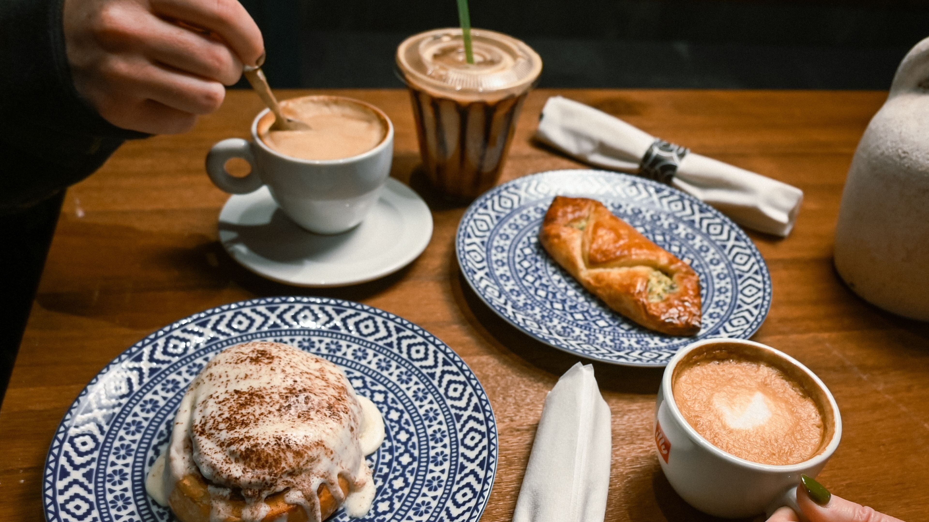 A table with a cup of coffee, a pastry, and a plate with a dessert.
