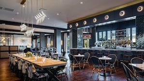 A modern restaurant with a bar area, wooden tables, and chairs.