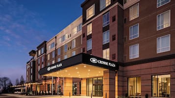 Un hotel de varios pisos con un llamativo letrero 'CROWNE PLAZA', que presenta fachada de ladrillo y amplias ventanas.