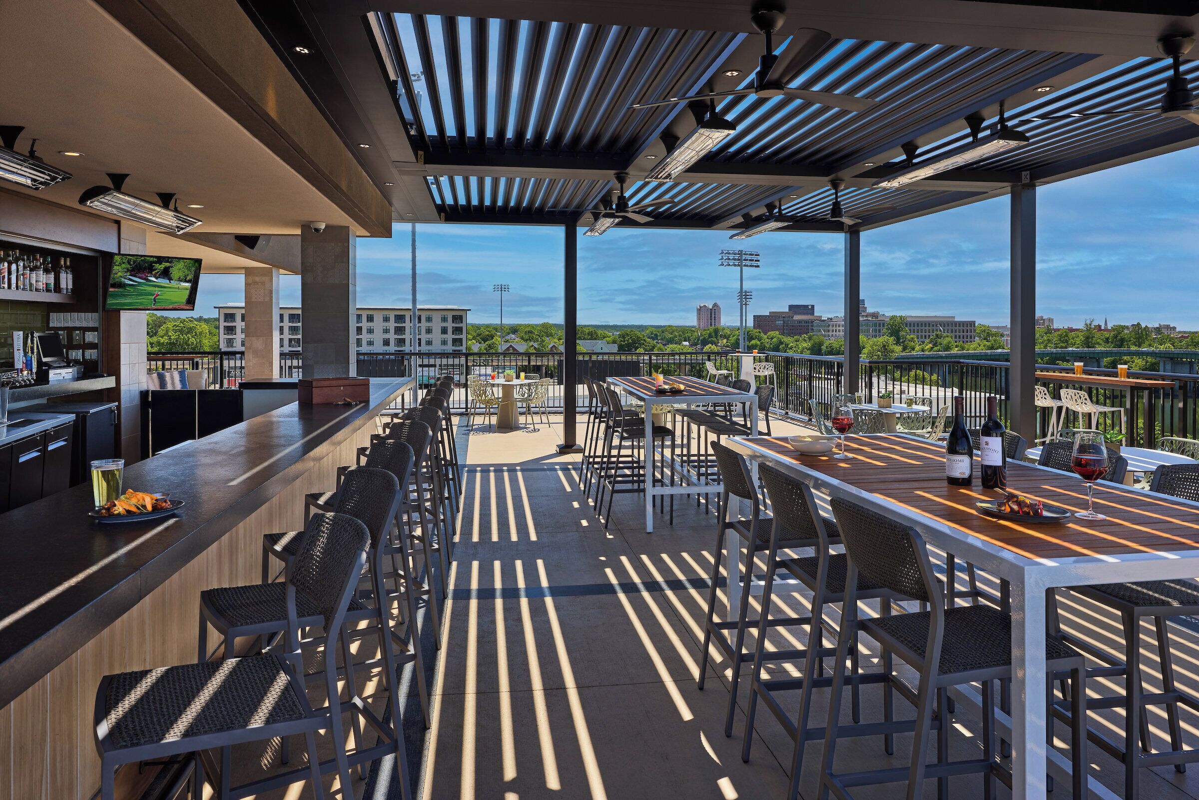 An outdoor bar area with multiple seating options and a view of the cityscape.