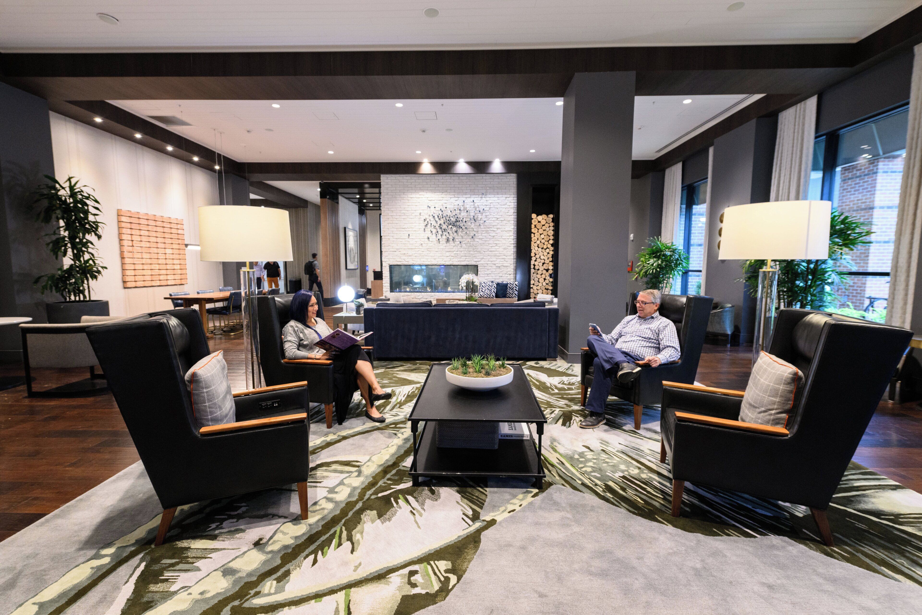 A modern lobby with a reception desk, seating area, and large windows.