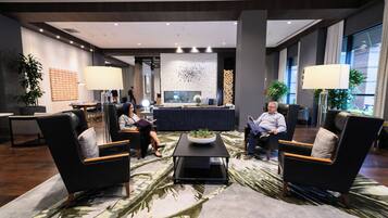 A modern lobby with a reception desk, seating area, and large windows.