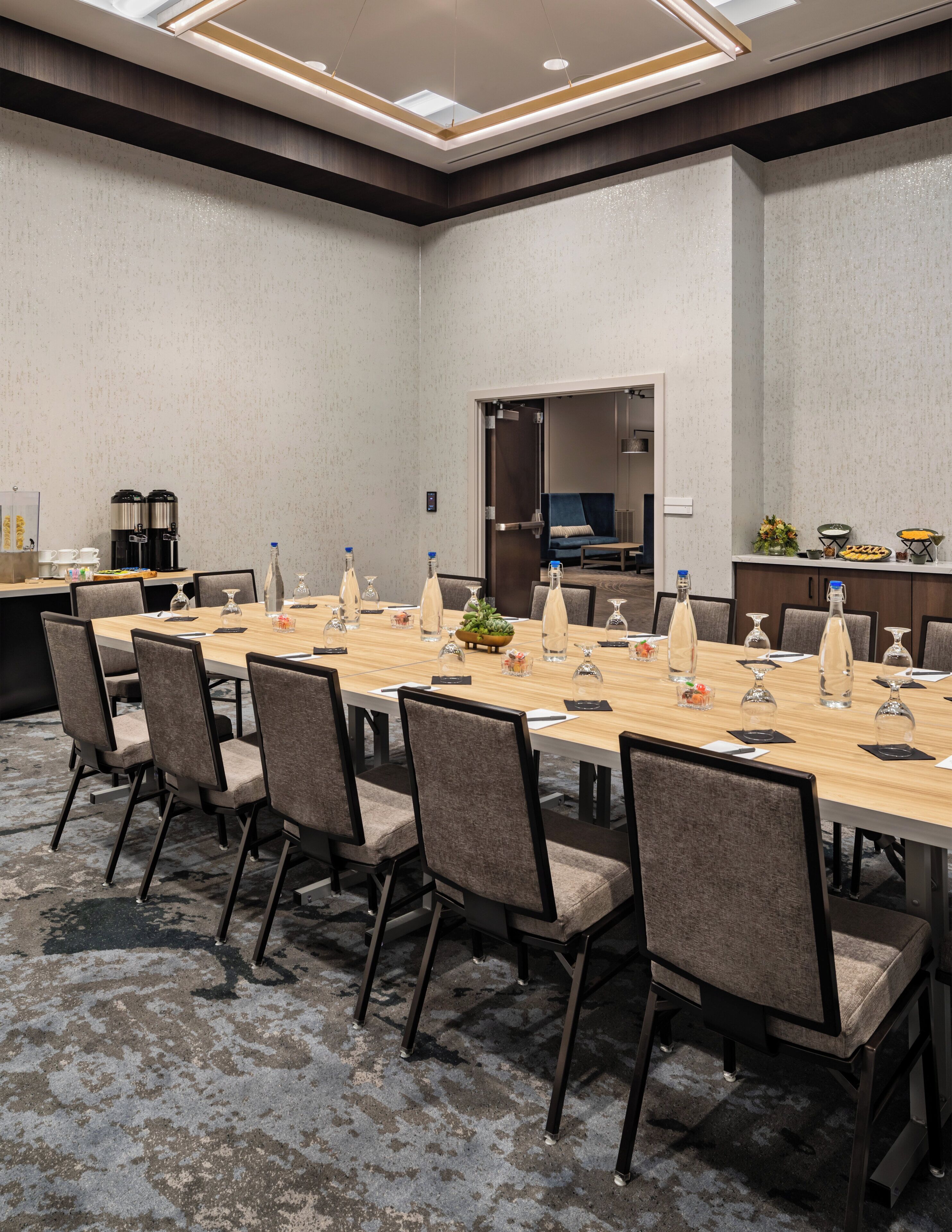 A conference room with a long table, chairs, and a coffee station.