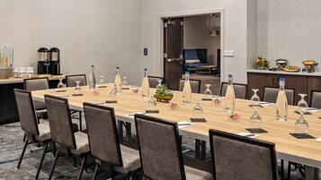 A conference room with a long table, chairs, and a coffee station.