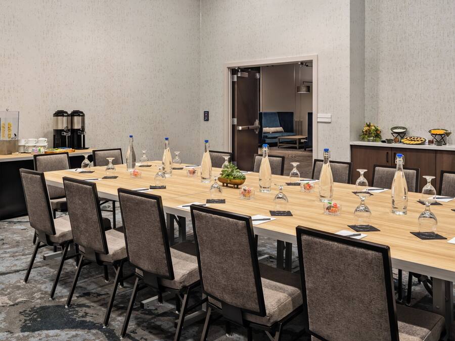 A conference room with a long table, chairs, and a coffee station.