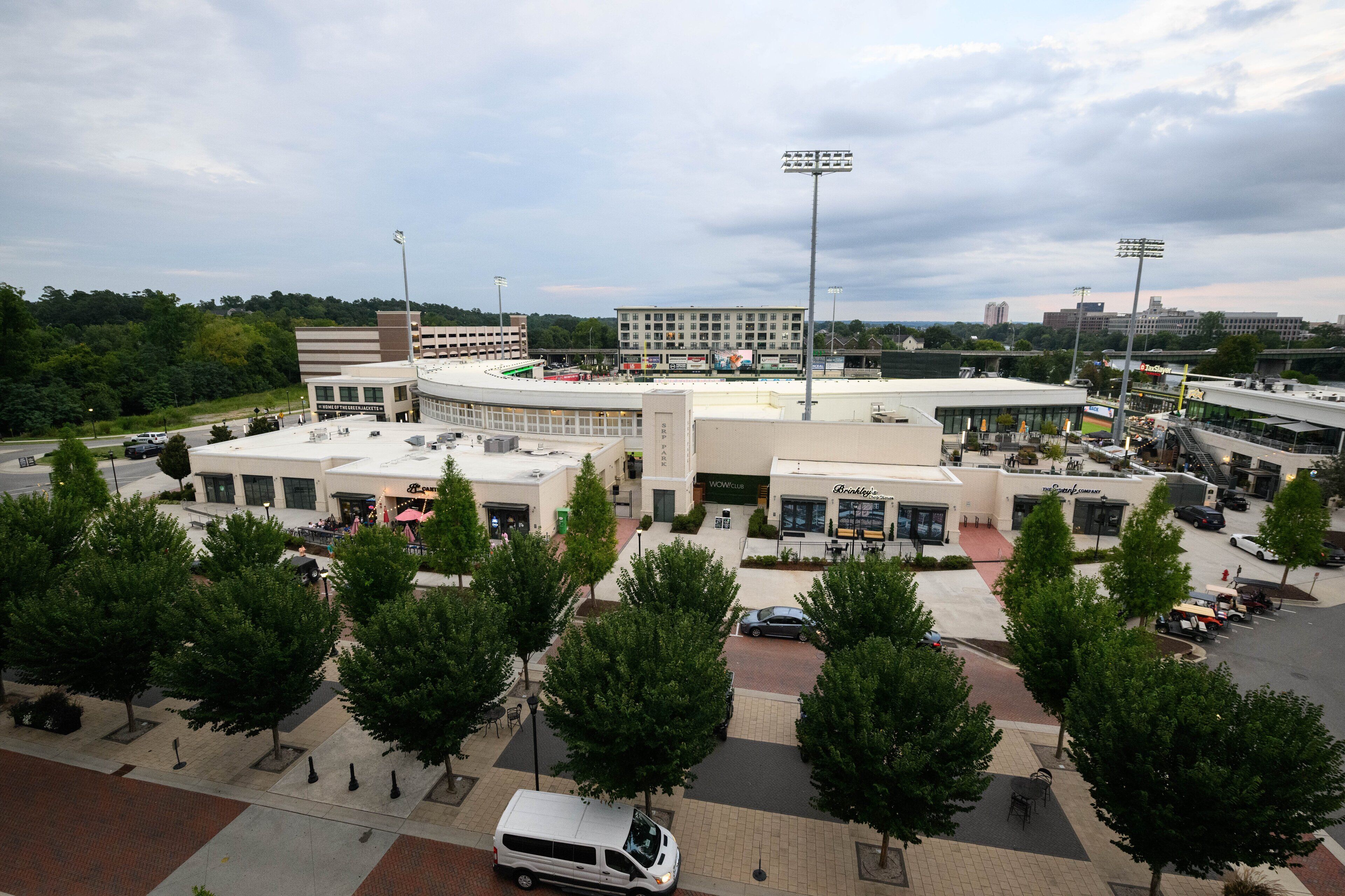 A stadium with a parking lot, surrounded by trees and buildings.