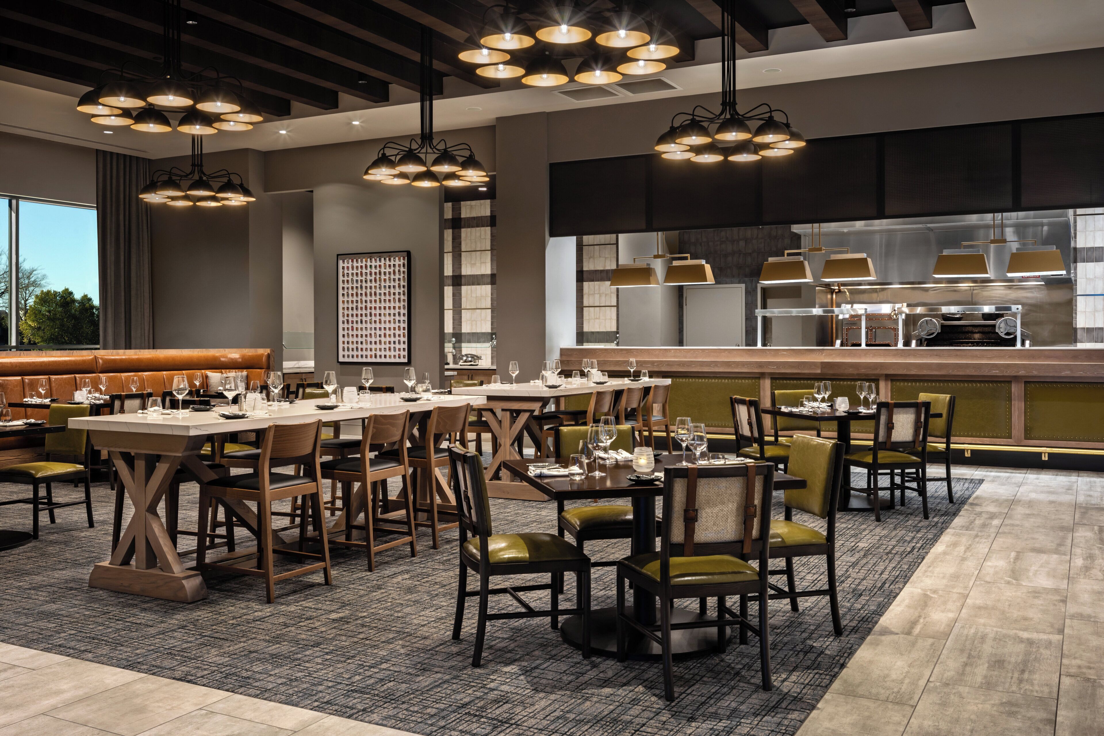 Een restaurant met meerdere eettafels, stoelen en hangende lampen.