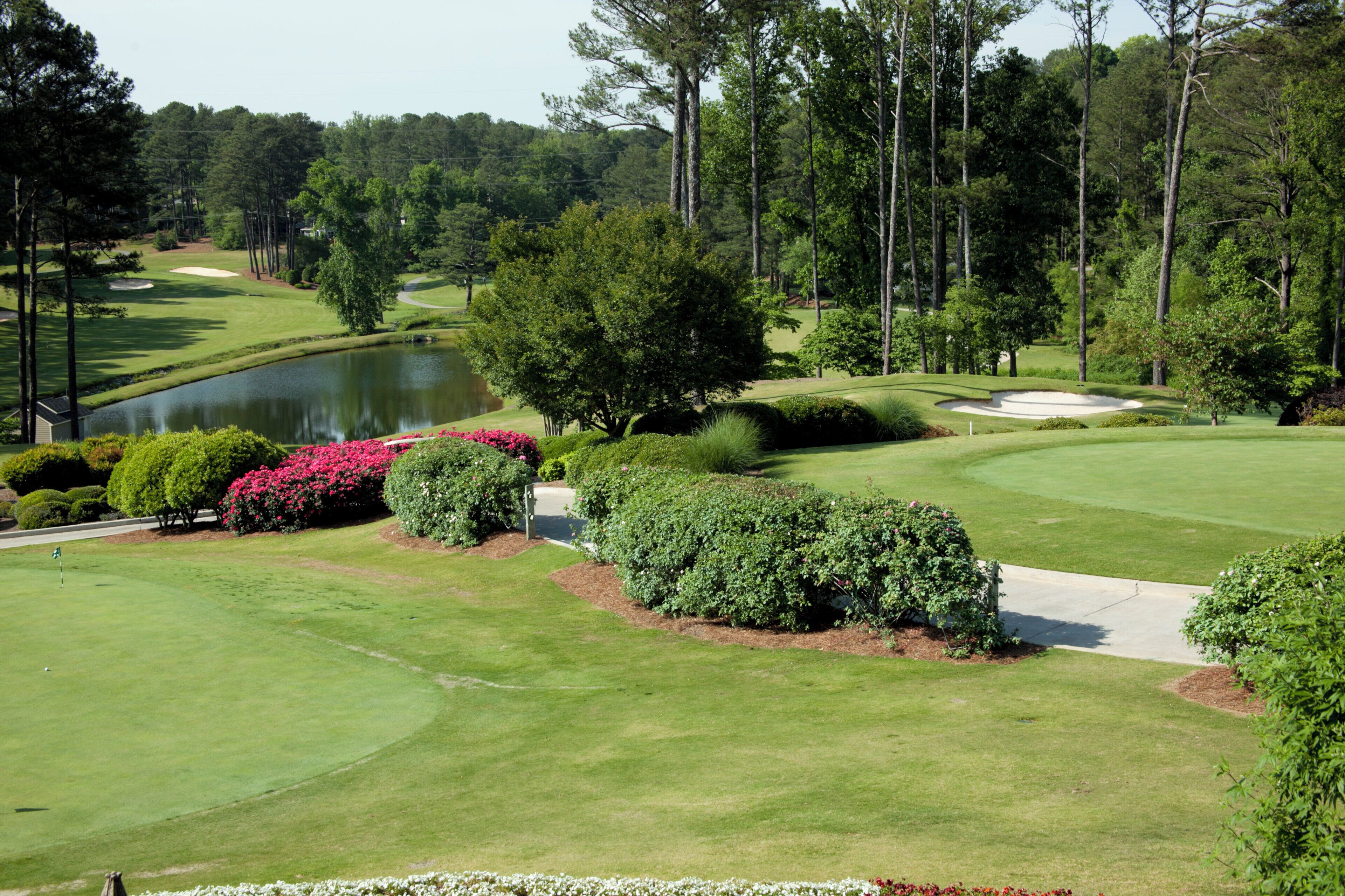 A golf course with a pond, sand bunkers, and well-maintained grass.