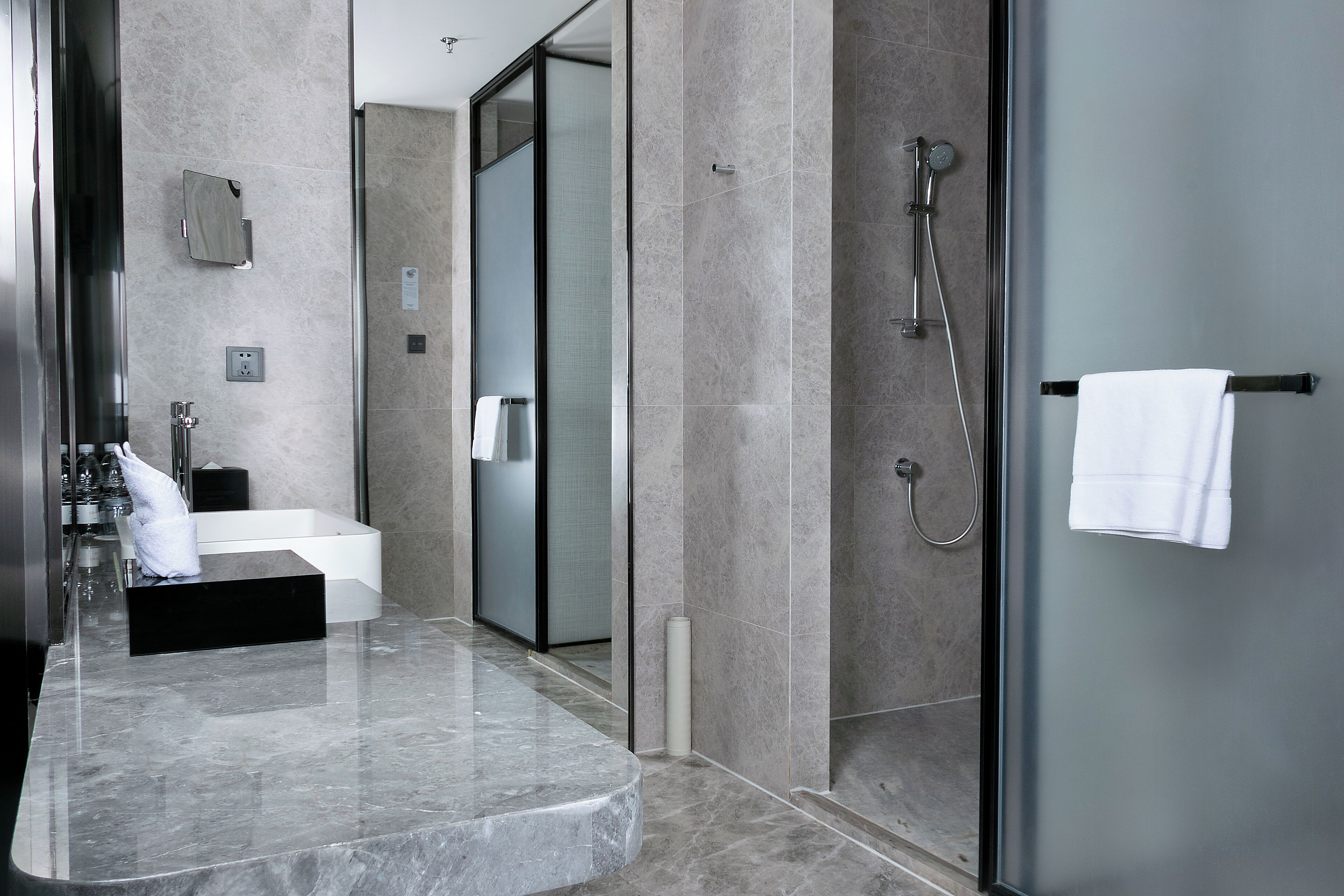 Ein modernes Badezimmer mit Marmorplatte, Duschkabine aus Glas und Handtuchhalter.