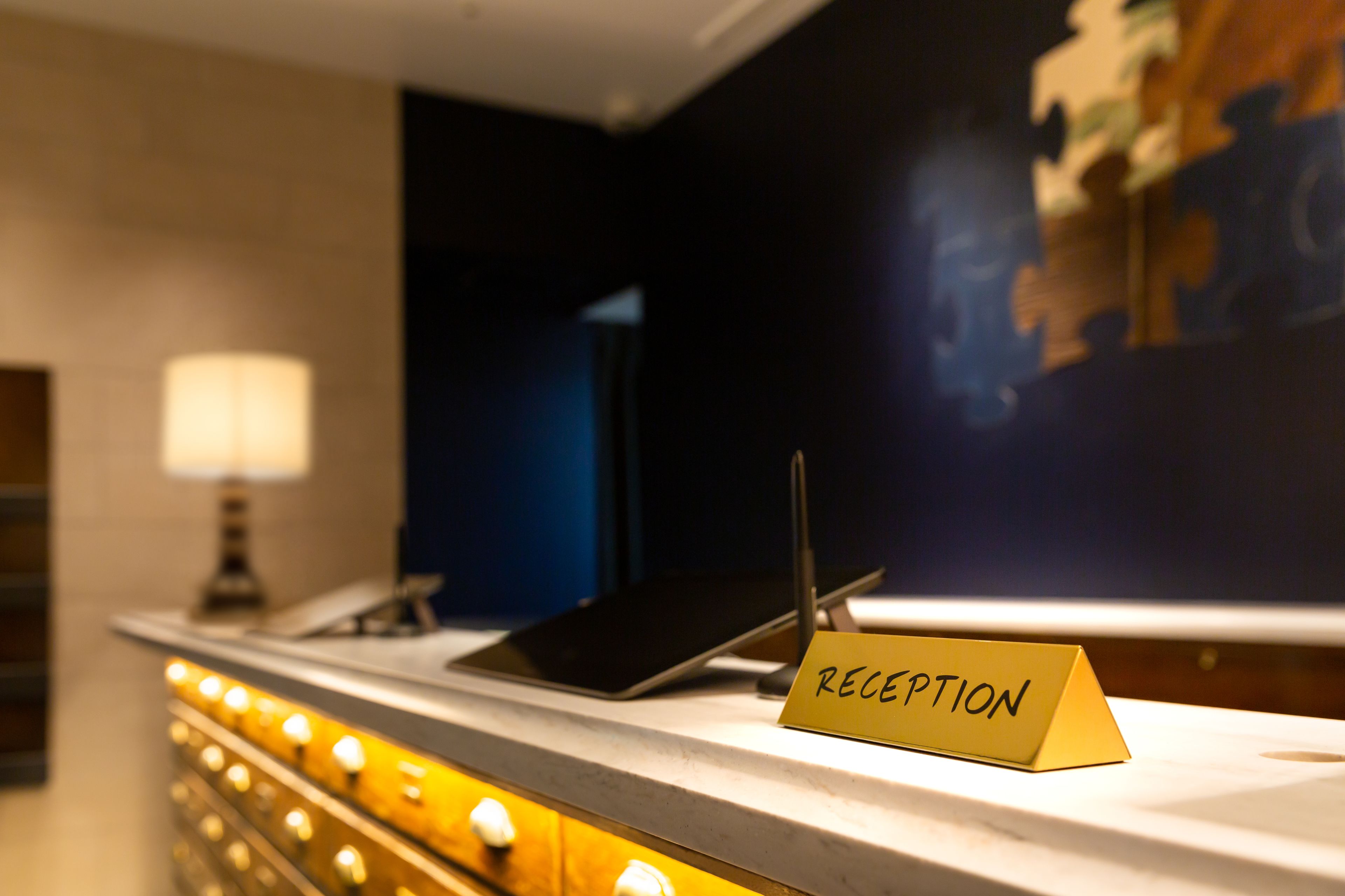 En reception med et skilt med teksten 'RECEPTION', en lampe og en tablet.