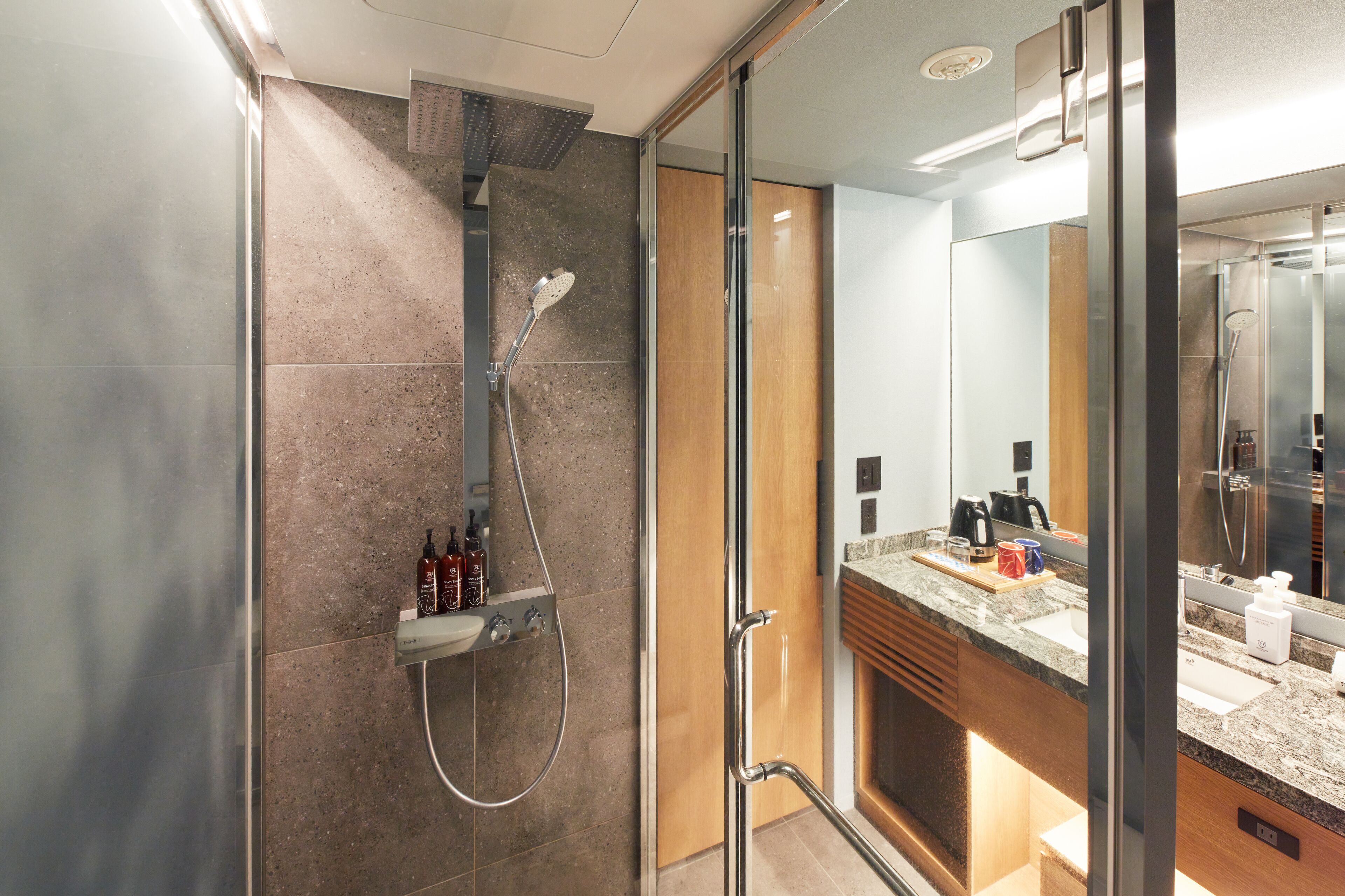 A modern bathroom with a shower, vanity, and large mirror.