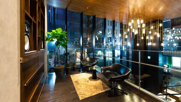 Un intérieur moderne avec une grande fenêtre, une plante en pot et un coin salon agrémenté d’un tapis.