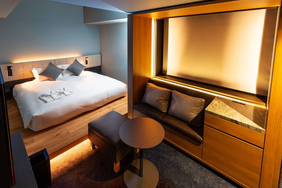 Moderni hotellihuone, jossa on suuri sänky, pieni oleskelualue, työpöytä ja suuri ikkuna.