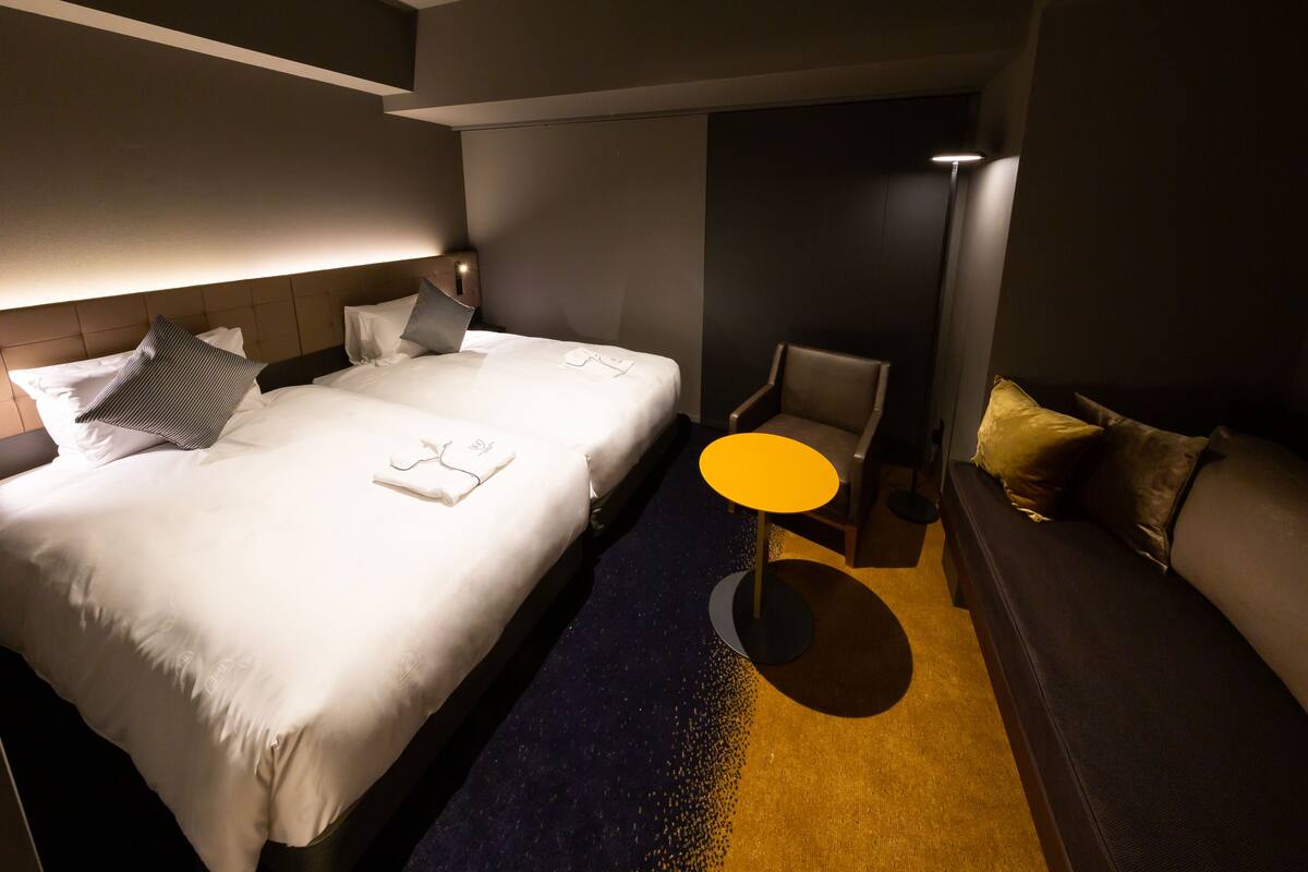 Hotellihuone, jossa on suuri sänky, pieni pyöreä pöytä, sohva ja tuoli.