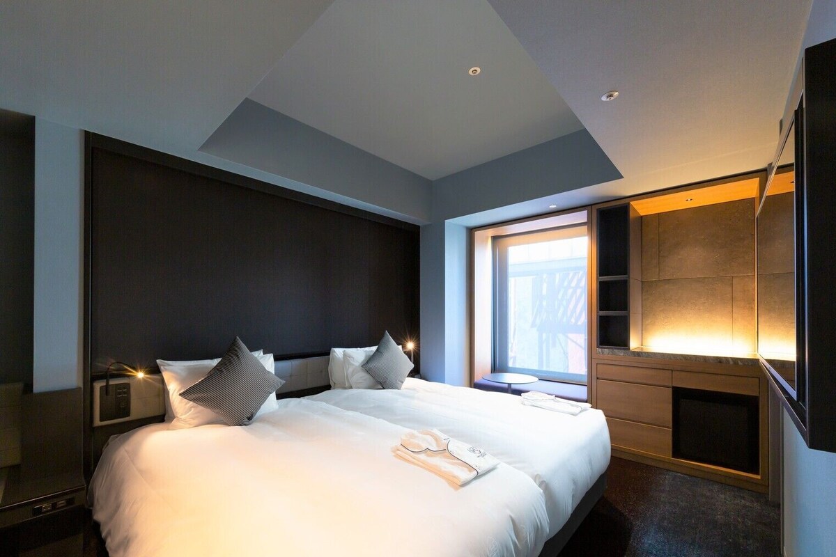 Een moderne hotelkamer met een groot bed, nachtkastjes, een televisie en een raam met uitzicht.