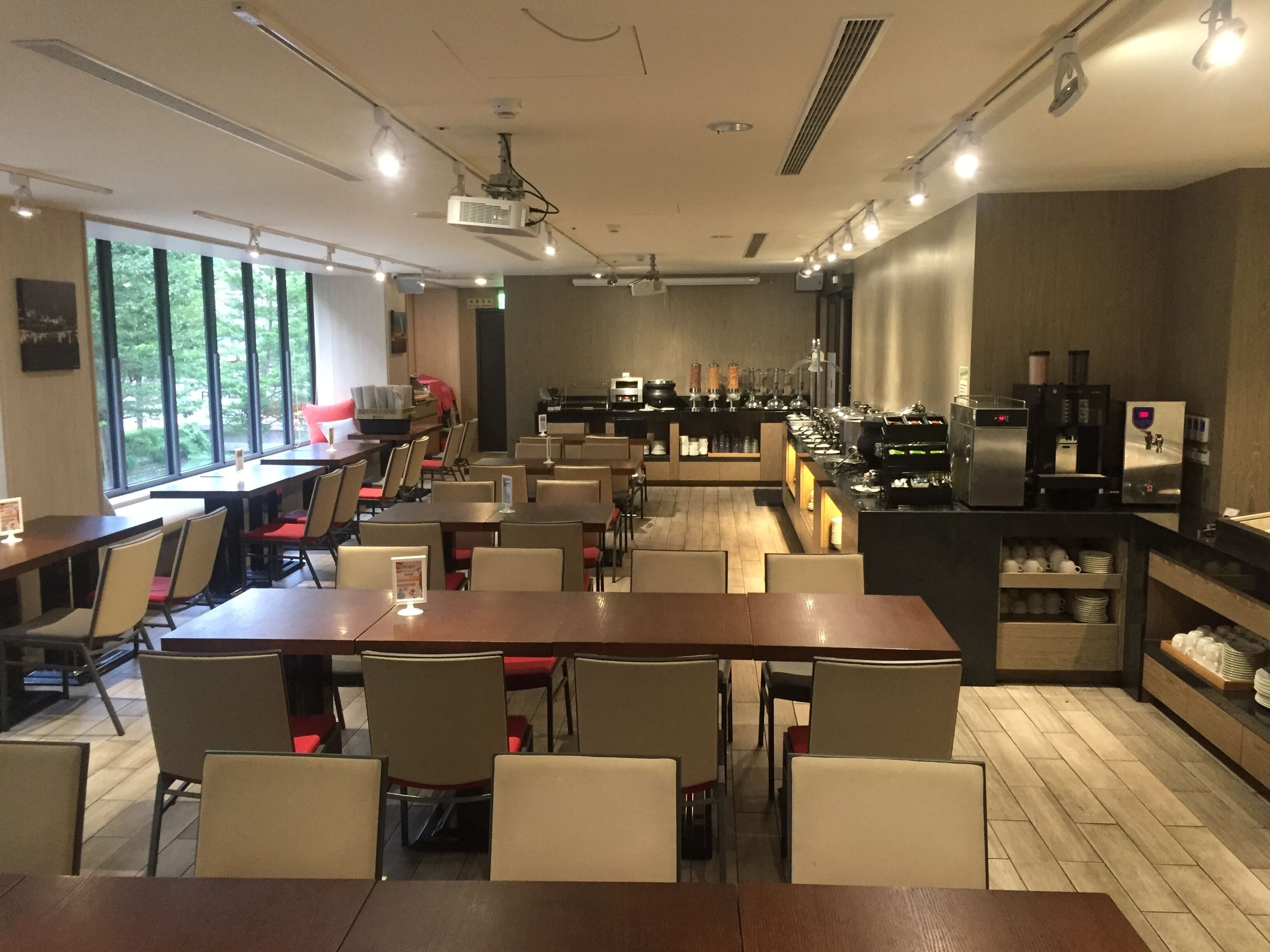A restaurant with multiple tables and chairs, a buffet area, and a coffee machine.