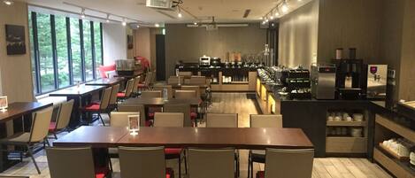 A restaurant with multiple tables and chairs, a buffet area, and a coffee machine.