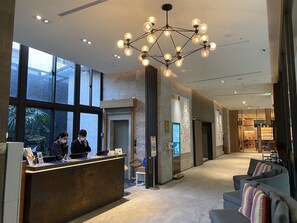A modern hotel lobby with a reception desk, large windows, a chandelier, and seating area. - Icasa By GoGo Hotel (Taichung)