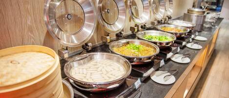 A buffet with various food items and utensils.